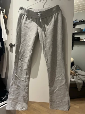 Grå bootcut mjukisbyxor  - Snygga grå mjukisbyxor med utsvängda ben och bred resår i midjan samt dragsko för skön passform. Tillverkade i mjukt sweatshirtmaterial som känns riktigt bekvämt. Perfekta för chill dagar eller när du vill ha en avslappnad stil. Strl M men passar en S så att den inte sitter så tajt.