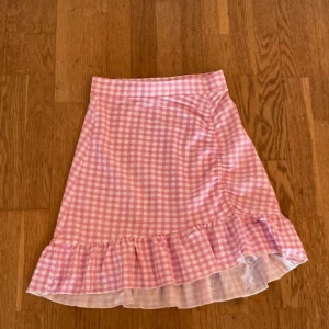 Rutig sommarkjol från Gina Tricot - Söt rutig sommarkjol från Gina med volang och asymmetrisk skärning, stl XS.