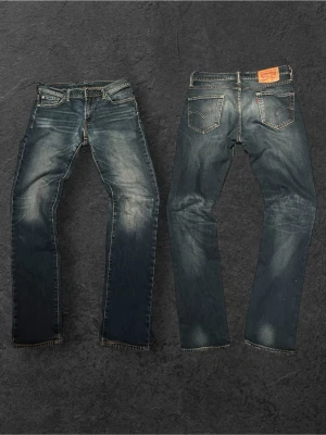 Vintage Levi's Jeans med go tvätt - Klassiska blå jeans från Levi's med straight fit och snygga slitningar framtill. Jeansen har fem fickor, gylf med dragkedja och knapp samt kontrastsömmar. Tillverkade i slitstarkt denim med en cool tvättad look.