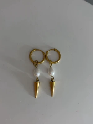 Örhängen   - Guld örhängen med pärlor och nitar som jag köpt här på plick. Aldrig använt. Säljer då det inte är min stil