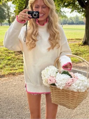 Vit stickad tröja med rosa detaljer - Säljer en vit stickad tröja med  hög krage och snygga rosa detaljer vid hals, ärmslut och nederkant. Tröjan har långa ärmar och är perfekt för lager på lager. Materialet är mjukt och mysigt. Endast använd 1 gång tidigare.