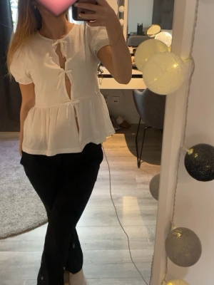 Vit blus med knyt och puffärm - Söt vit blus med tre knyt framtill och puffiga korta ärmar. Blusen har en luftig passform och volang nedtill. Blusen är från Gina tricot young i storlek 170, men passar mig som brukar ha XS/S i toppar! 