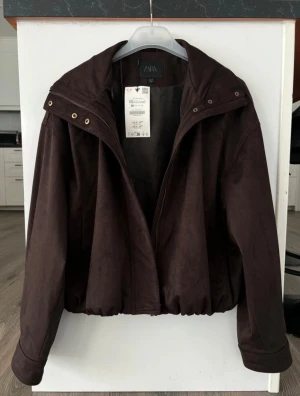 Mörkbrun jacka från ZARA - Säljer en mörkbrun mockajacka från Zara med prislapp kvar. Perfekt till våren.