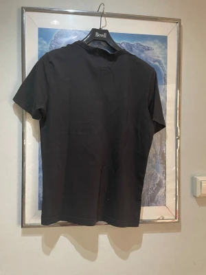 Svart Puma t-shirt med logga - Klassisk svart t-shirt från Puma med vit logga på bröstet. T-shirten har rund halsringning och korta ärmar. Tillverkad i mjuk bomull som känns skön mot huden. Perfekt till en avslappnad och sportig stil.