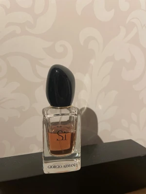 Giorgio Armani Sì Eau de Parfum - Elegant parfym från Giorgio Armani, Sì Eau de Parfum. Flaskan är rektangulär i genomskinligt glas med svart, rundad kork och har en mjukt rosa vätska. Stilsäker design som känns lyxig och modern.