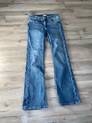 Blå bootcut jeans med strassdetalj - Säljer ett par blå bootcut jeans med glittriga detaljer på fickorna✨
