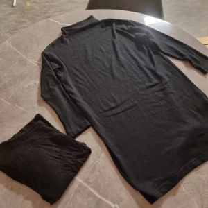 Paket - Svart långärmad poloklänning samt svart tshirt  - En svart långärmad klänning med polokrage i mjukt material. Enkel och stilren design som passar perfekt till lager-på-lager eller som den är. Klänningen har en rak passform och är knälång. Perfekt för dig som gillar minimalistisk stil. Svart tshirt från h&m