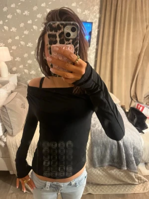 Svart offshoulder topp - Snygg svart offshoulder topp med lång ärm och tight passform. Toppen har en enkel och stilren design som passar perfekt till jeans eller kjol. Materialet känns mjukt och stretchigt, vilket gör den bekväm att bära hela dagen.