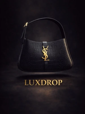 Svart YSL handväska i krokopräglat läder - Snygg svart handväska från Saint Laurent med krokopräglat läder och ikonisk guld YSL-logga framtill. Väskan har en stilren axelrem och elegant form som ger en lyxig vibe. Perfekt för dig som vill ha en statement piece i garderoben.✨