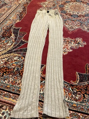 Grå ribbade leggings med slits - Snygga grå leggings med bred ribbad struktur och slitsar nertill på benen. De har hög midja och är stretchiga för en bekväm passform. Perfekta till en avslappnad look och passar till sneakers eller boots.