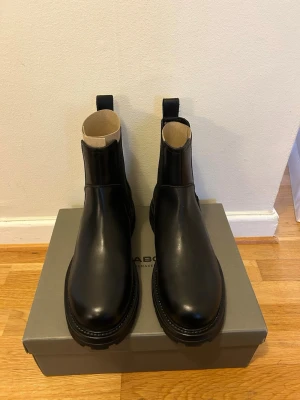 Svarta Chelsea boots från Vagabond - Stilrena svarta Chelsea boots från Vagabond i slätt läder. Klassisk siluett med elastiska paneler på sidorna och grov sula. Aldrig använda, köpt fel storlek. Originalpris 1900kr 