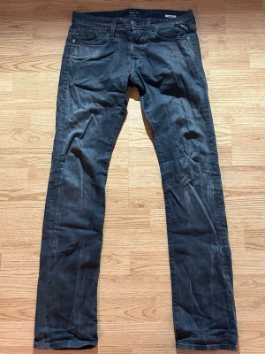 Svarta slim fit jeans från Replay - Snygga svarta slim fit jeans från Replay med klassisk femficksdesign och diskreta slitningar. Jeansen har låg midja och raka ben, perfekta för en trendig och avslappnad look. Materialet är mjukt och stretchigt för extra komfort.