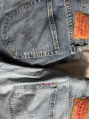 Levi's ljusblå raka jeans - Klassiska ljusblå jeans från Levi's med raka ben och femficksmodell. Jeansen har den ikoniska röda Levi's-lappen på bakfickan och patch i läder bak i midjan. Perfekta för en avslappnad och trendig look. Jag tror nya kostar runt 700kr st. 200 kr styck