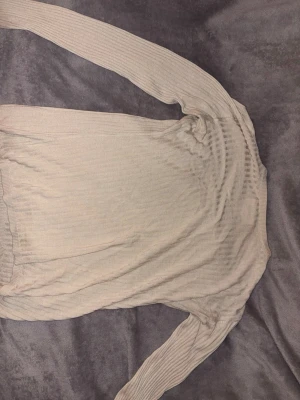 Beige ribbstickad tröja - Ljusbeige, tunn och ribbstickad tröja med lång ärm och rund hals. Tröjan har en enkel och stilren design som passar till det mesta. Materialet ser ut att vara mjukt och stretchigt, perfekt för lager på lager.