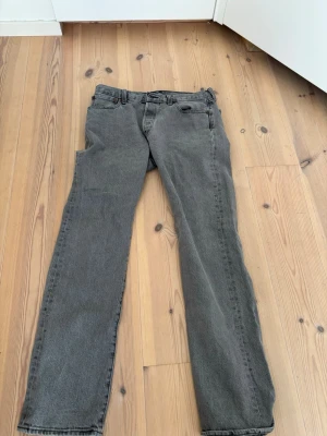 Grå raka jeans från Levi's - Säljer ett par grå Levi's jeans med rak passform och klassisk femficksdesign. Jeansen har en diskret tvätt och är tillverkade i slitstark denim. Perfekta för en avslappnad och stilren look.