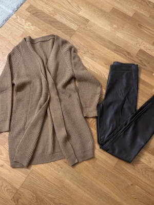 Beige lång kofta i grovstickad modell - Byxor i läderlook från Cubus + stickad kofta från Shein, stl S Fint skick, säljs gärna tillsammans eller separat. Pris: 90 