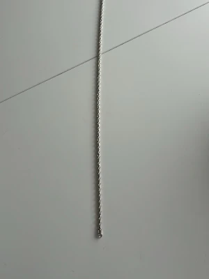 Silverfärgat tvinnat halsband - Snyggt halsband i silverfärg med tvinnad kedja som ger ett stilrent och modernt intryck. Halsbandet har en enkel design utan hänge och passar perfekt till olika stilar. Materialet ser ut att vara metall med blank finish.