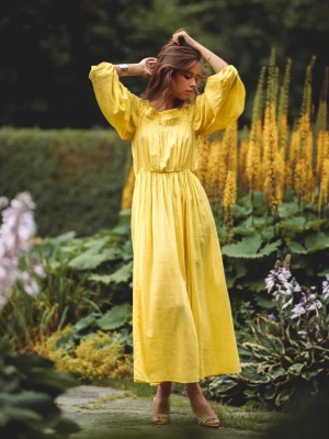 Gul klänning med puffärmar  - En ljusgul lång klänning med breda puffärmar och smockad överdel. Klänningen har en luftig och flowy passform, perfekt för varma dagar. Materialet ser ut att vara lätt och naturligt, troligen bomull eller linne. Ingen synlig logga eller märke.