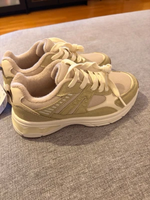 Beige sneakers från Primark - Snygga beige sneakers från Primark. Skorna har vita detaljer, klassisk snörning och en chunky vit sula. Perfekta för en avslappnad och trendig stil. Helt nya