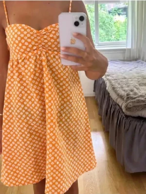 Söt orange klänning - Säljer denna sååå fina orange klänningen med vita blommor. Den är jättefin särskilt på sommarn när man är brun!!💕💕💕🧡🧡