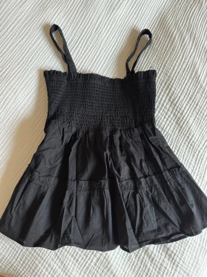 Svart smockad topp - Snygg svart topp med smockad överdel. Även snygg öppning i ryggen. 