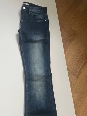 Mörkblå bootcut jeans - Snygga mörkblå bootcut jeans med klassisk femficksdesign och ljusa slitningar framtill. Från Gina tricot aldrig använda, passar 32/34 och jag är 168 perfekt i längd