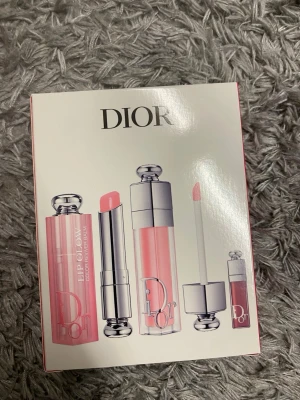 Dior Lip Glow läppbalsam set - Exklusivt läppbalsam set från Dior med tre produkter i olika rosa nyanser. Förpackningen är vit med silver- och rosa detaljer samt ett hjärtmotiv av fjärilar. Produkterna har elegant design med silverlock och transparent hylsa. Perfekt för dig som vill ha återfuktade och glansiga läppar.