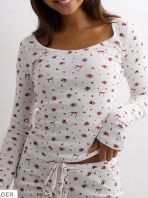 Vit/röd pyjamas från nelly - Mysig tvådelad pyjamas i vit färg med små röda blommor och rosetter. Setet består av en långärmad topp med rundad halsringning💕