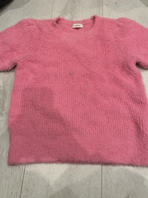 Rosa fluffig stickad tröja Vero Moda - Mysig rosa stickad tröja från Vero Moda med korta ärmar och rund hals. Tröjan har en fluffig, mjuk struktur som ger en trendig look. Perfekt för dig som gillar färg och vill ha något bekvämt och snyggt i garderoben. De är ingen fläck utan det är ljuset💕