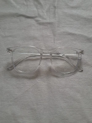 Transparenta solglasögon i retrostil - Snygga solglasögon med transparent båge och rundad form. Glasögonen har en modern och stilren look som passar till de flesta outfits. Tillverkade i syntetmaterial och har en klassisk design utan synligt märke.