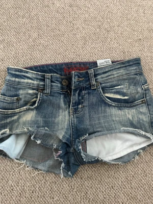 Blå slitna jeansshorts  - Säljer ett par as snygga blå jeansshorts med slitna detaljer. Klipptes från ett par jeans till shorts och är använda ett fåtal gånger. Hör av er över funderingar och eller fler bilder