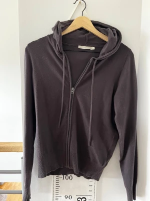 Mörkgrå hoodie från 157 - Mysig mörkgrå hoodie med dragkedja från 157. Modellen har huva med dragsko och ribbade muddar vid ärmslut och nederkant. Perfekt för en avslappnad och chill stil. Materialet känns mjukt och följsamt.