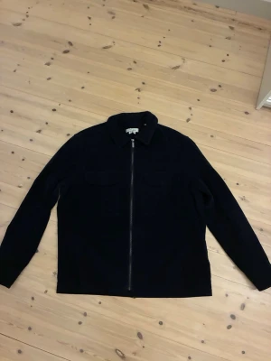 Mörkblå manchester overshirt Strömberg - Snygg mörkblå overshirt från Strömberg i mjuk manchester. Jackan har dragkedja framtill, två bröstfickor med lock och klassisk krage. Perfekt lager på lager-plagg för en stilren och avslappnad look.