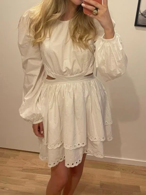 Lovisa Barkman X Bikbok klänning - Söt vit kort klänning med långa puffärmar, markerad midja och cut-outs vid sidorna. Kjolen är volangig med broderade spetsdetaljer längs kanterna. Perfekt för sommarens alla tillfällen. Från Lovisa Barkman kollektion för Bikbok. Är egentligen en storlek M men har sytt in midjan för att passa mig som är S. En hake längst upp har gått av (syns på sista bilden)