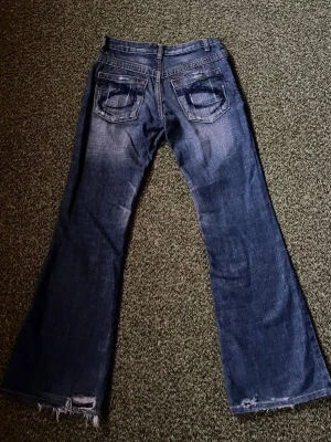 Blå bootcut jeans med slitningar - Ett par blå bootcut jeans med slitna detaljer från Red Pepper. Storlek: W24-25