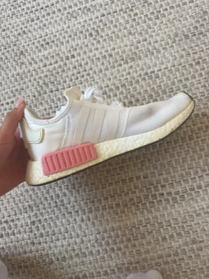 Vita Adidas NMD R1 sneakers - Säljer ett par vita Adidas NMD R1 sneakers med rosa detaljer på sulan. 
