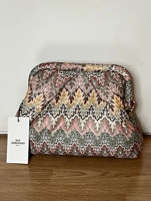 Beck Söndergaard Pala Bonita Bag. Ny, oanvänd. - Slutsåld överallt! Pala Bonita Bag är en av Becksöndergaards mest populära väska. Clutch i tyg, stängs med metallram, mått 26 x 18 cm. Invändigt finns ett fack med dragkedja. Kvitto finns.