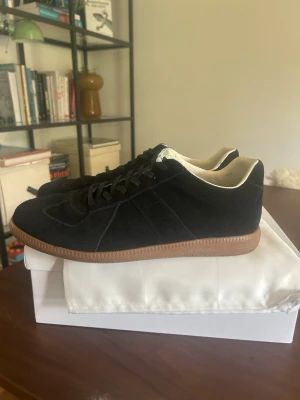 Svarta Maison margiela  - Tjena, säljer ett par Maison margiela skor i svart, storlek 43, skick 7/10, dem har varit använda 10 gånger ungefär, är i mycket gott skick, inga defekter eller hål bara lite slitna på undersidan men inget mer än de, fraktas samma dag som köpt 📦