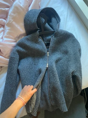 Grå ribbad hoodie från BikBok - Mysig grå hoodie från BikBok i ribbat stickat material. Tröjan har dragkedja framtill, huva och långa ärmar. Perfekt för en chill och avslappnad stil. Passar dig som gillar bekväma och snygga plagg.