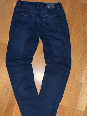 Mörkblå raka jeans - Snygga mörkblå jeans med raka ben och klassiska bakfickor. Jeansen har en enkel design utan slitningar och är tillverkade i ett mjukt denimtyg. Passar perfekt till en avslappnad stil och har bälteshällor i midjan.