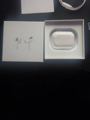 Apple AirPods Pro med laddningsetui - Säljer ett par Apple AirPods Pro i vitt med tillhörande laddningsetui och originalförpackning. Trådlösa in-ear-hörlurar med stilren design och silikonproppar för bra passform. Perfekta för musik, samtal och träning.