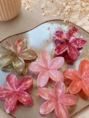 Blommiga hårklämmor i pastellfärger - Säljer superfina hårklämmor formade som blommor i olika pastelliga nyanser av rosa, rött, orange och grönt. Klämmorna har en glansig, marmorerad finish och är perfekta för att piffa upp frisyren. Materialet är plast. Skriv privat för färg!
