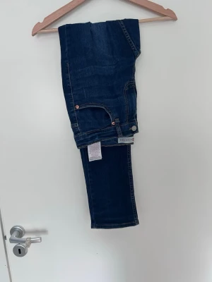 Mörkblå raka jeans från Gant - Snygga mörkblå jeans från gant med klassisk femficksmodell och raka ben. Jeansen har orangea sömmar och silverfärgad knapp. Tillverkade i stretchigt denimtyg för extra komfort. Perfekta till en avslappnad och trendig look.