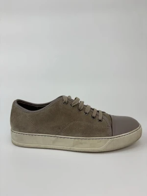 Beige Lanvin sneakers med mocka och läder - Stilrena sneakers i beige mocka med tåparti i matchande beige läder. Klassisk låg modell med snörning och vit sula. Perfekta för dig som gillar en clean och enkel look med en twist av olika material.