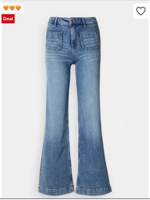 Blå utsvängda jeans med fickor - Snygga blå jeans med utsvängda ben och höga fickor framtill. Klassisk femficksmodell i mjukt denimtyg, perfekt för en trendig och avslappnad look. Stängs med knapp och dragkedja. Passar dig som gillar retrostil och vill sticka ut.