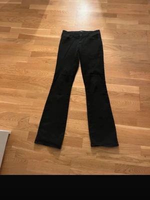 Svarta bootcut jeans från ONLY - Säljer ett par svarta bootcut jeans från ONLY med klassisk femficksdesign och normal midja. Jeansen har utsvängda ben och är tillverkade i en stretchig denim som sitter snyggt och bekvämt. Perfekta för dig som gillar en tidlös och trendig look.