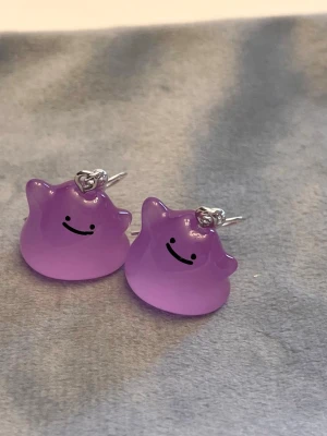 Självlysande Ditto örhängen Pokémon smycke  - Så gulliga örhängen med Ditto! Berlockerna är ca 1,5 x 1,5 cm. Den är också självlysande och lyser i mörkret.