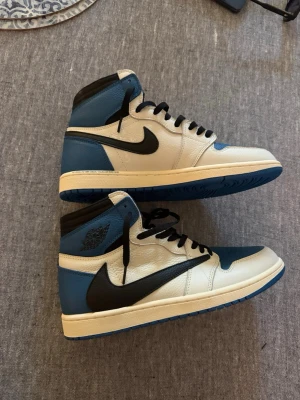 Nike Air Jordan 1 blå och vita sneakers - Säljer ett par Nike Air Jordan 1 sneakers i blått, vitt och svart. Skorna har högt skaft, svart swoosh och svarta skosnören. Tillverkade i läder med klassisk Air Jordan-logga på sidan. Perfekta för dig som vill ha en ikonisk och stilren look. Pris 1500 kr vid snabb affär kan pris diskuteras 