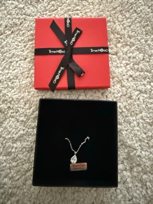 Silverhalsband Time Road  - Snyggt halsband från Time Road i äkta silver (925). Hängsmycket är droppformat och dekorerat med gnistrande stenar för extra bling. Kedjan är tunn och elegant, perfekt för att lyfta vilken outfit som helst. Kommer i original ask med svart inredning och röd presentförpackning.