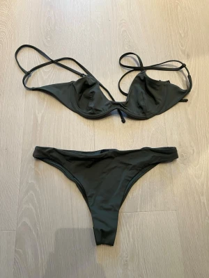 Mörkgrön bikini från Weekday, S - Snygg mörkgrön bikini från Weekday i modellen AVA Brazilian. Överdelen har tunna axelband och bygel, underdelen är en brazilian-modell. Materialet är stretchigt och snabbtorkande, perfekt för stranden eller poolen. Enkel och stilren design.